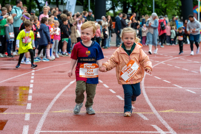 Twee kinderen gaan hand-in-hand over de finish